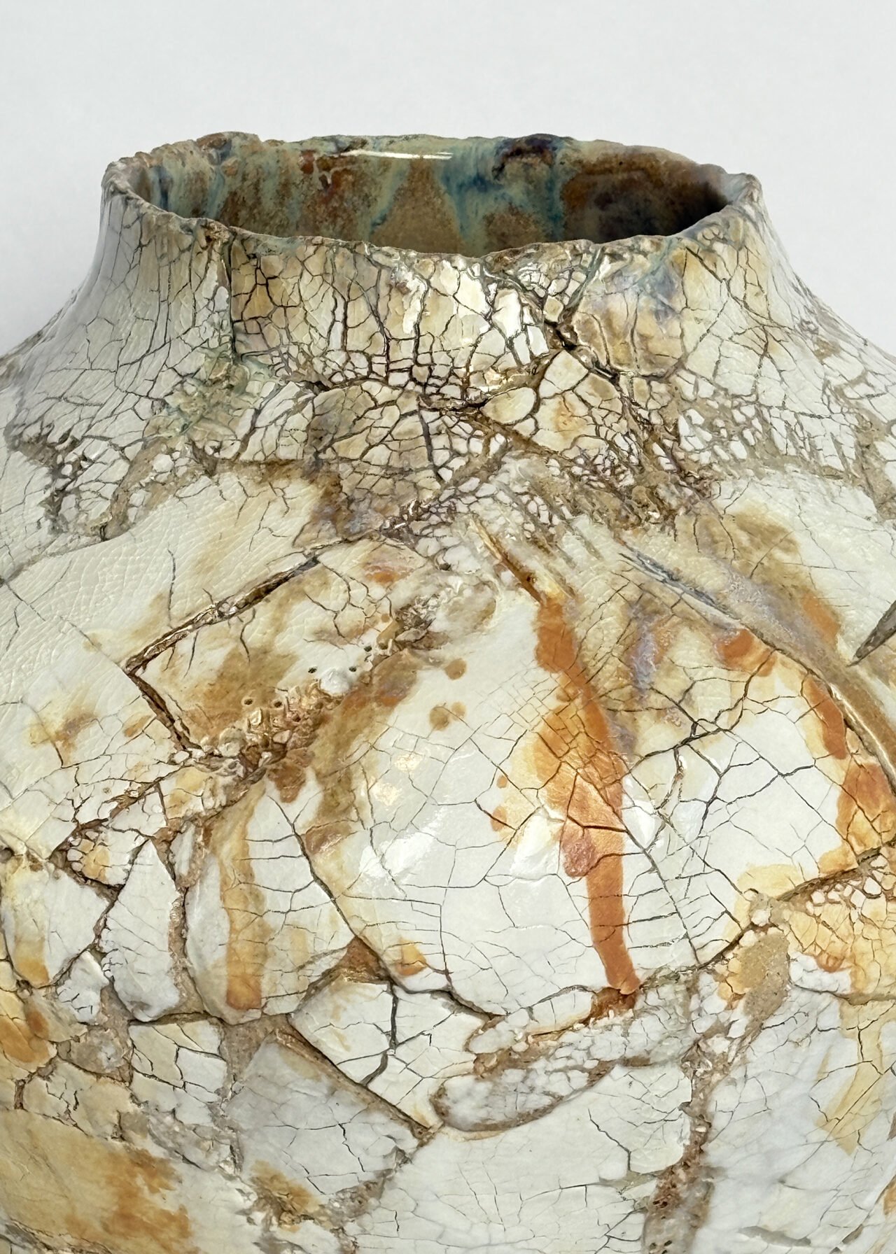 Handbuilt ceramic vessel with cracked textured surface and layered glaze