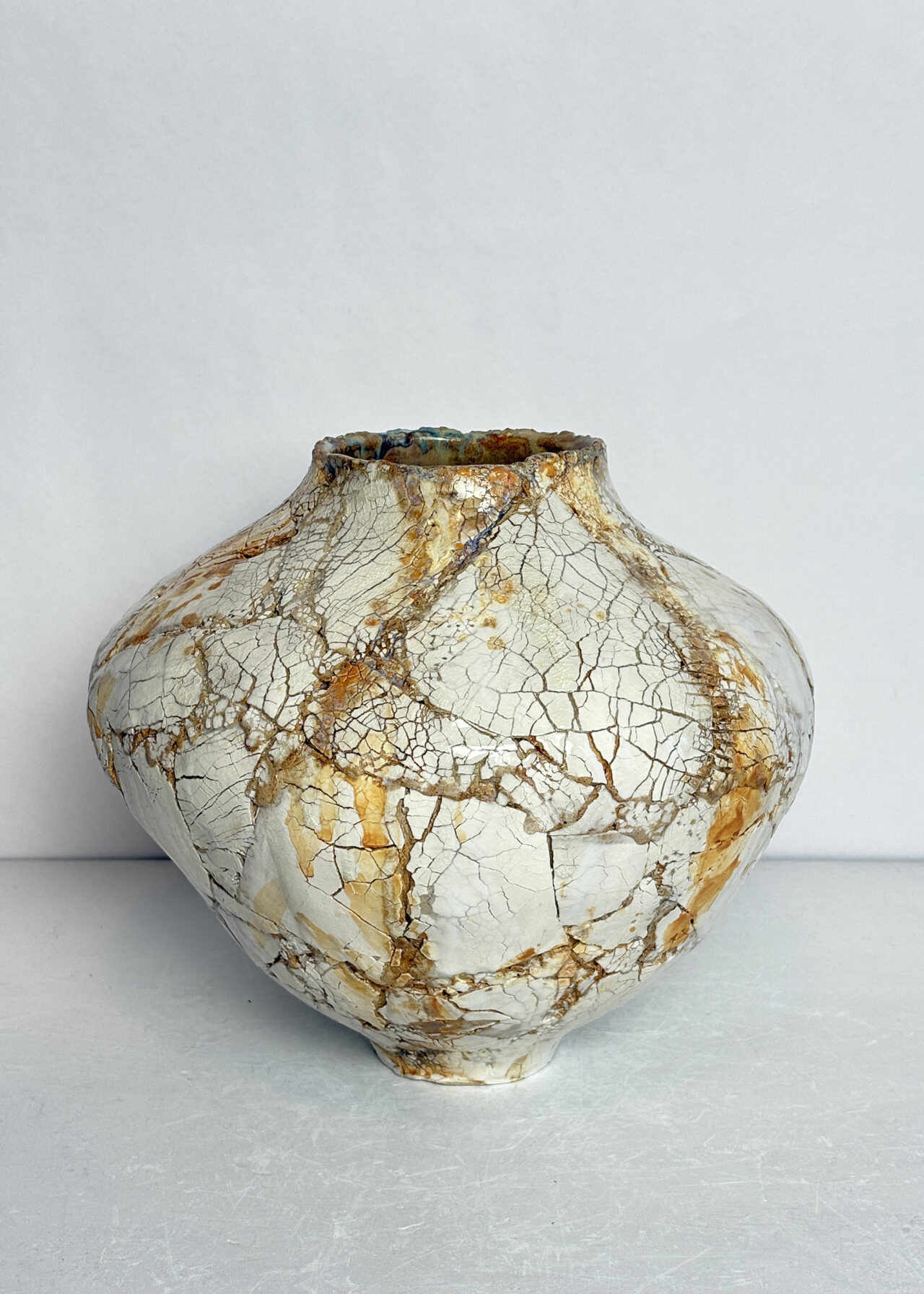 Contemporary ceramic vessel featuring blistered, fractured surface textures inspired by erosion and geological change