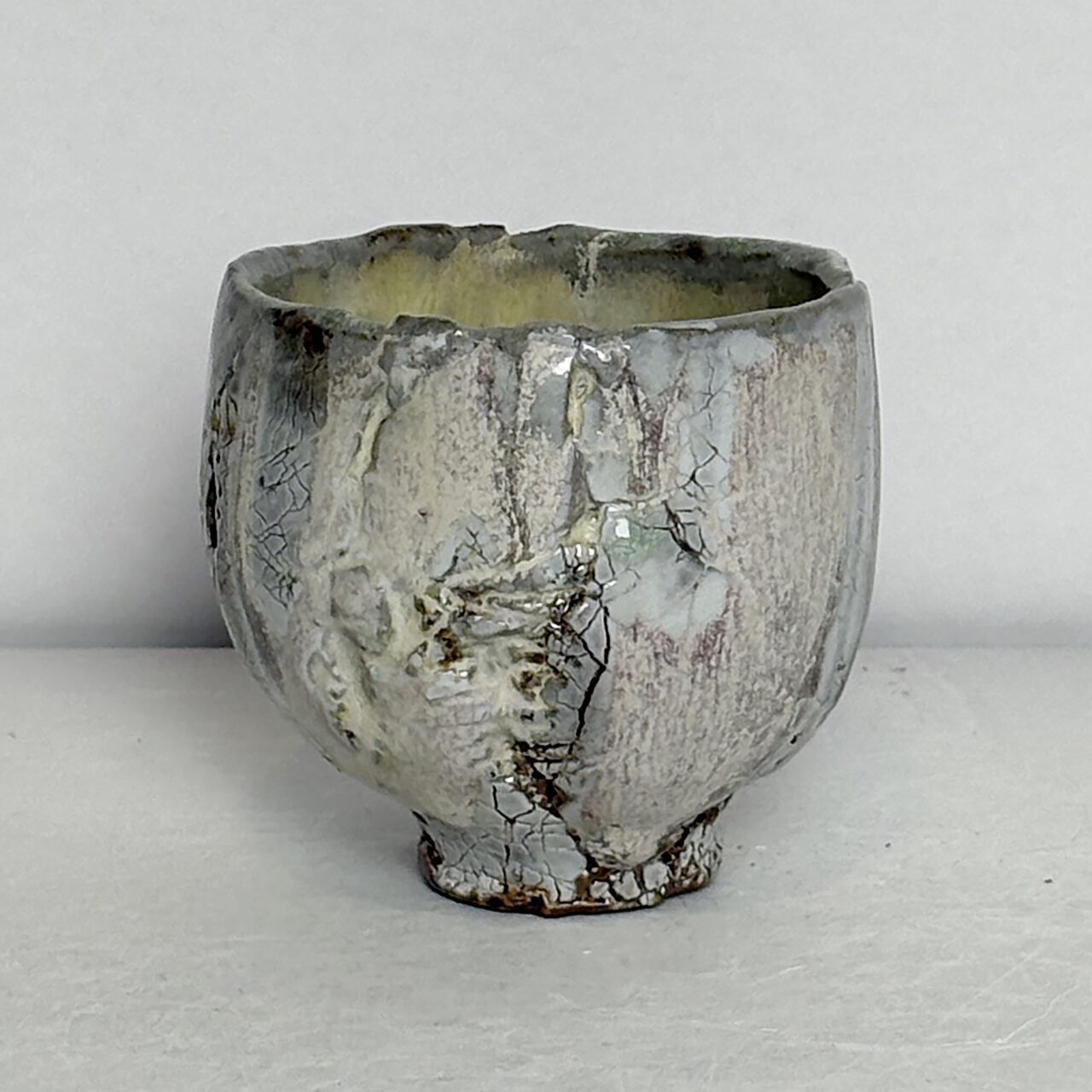 No. 74 Small ceramic vessel with soft gray and cream glaze, crackled surface, and subtle vertical textures with dark accents.