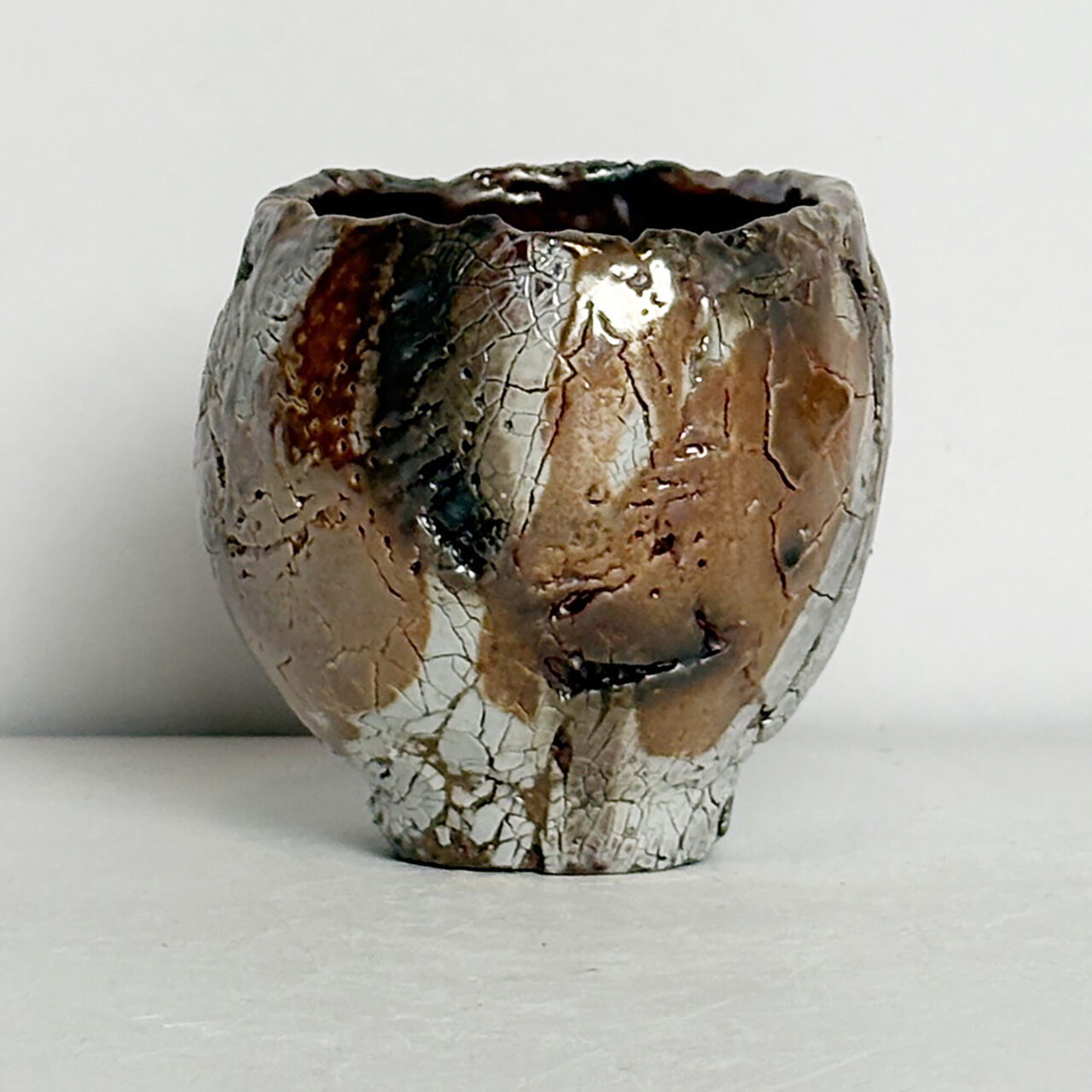 no. 79 Soda fired small ceramic vessel with white glaze, crackled surface, and layered brown and gray patches with soft transitions.