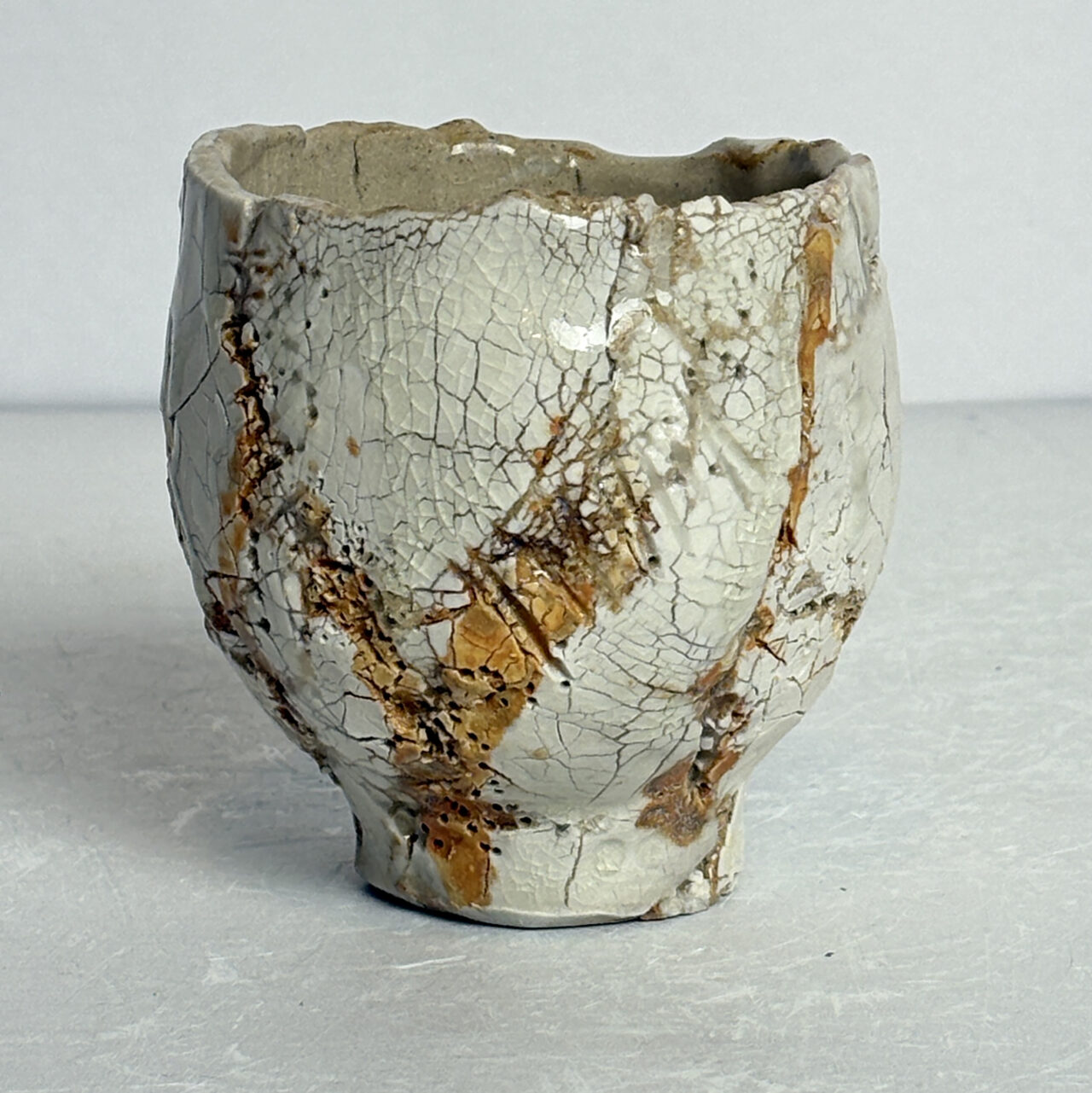 no. 81 Small ceramic vessel with white glaze, crackled surface, and soft brown and gray veining.