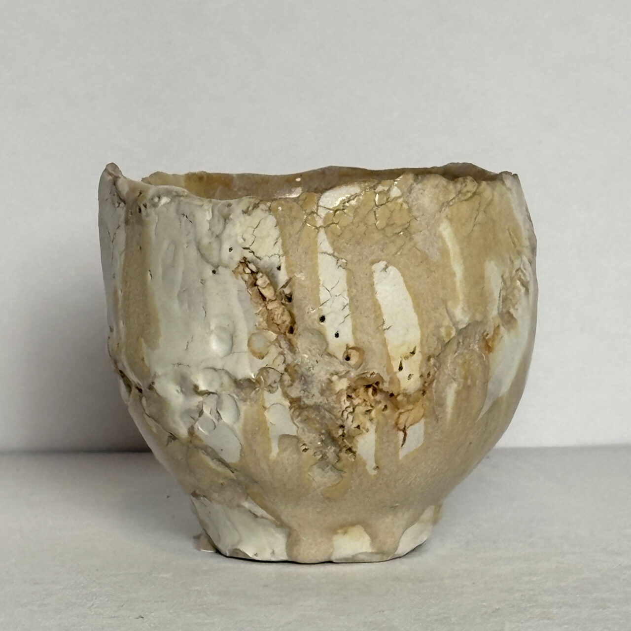 no. 86 Small ceramic vessel with pale glaze, crackled surface, and warm beige and cream tones with soft drips.