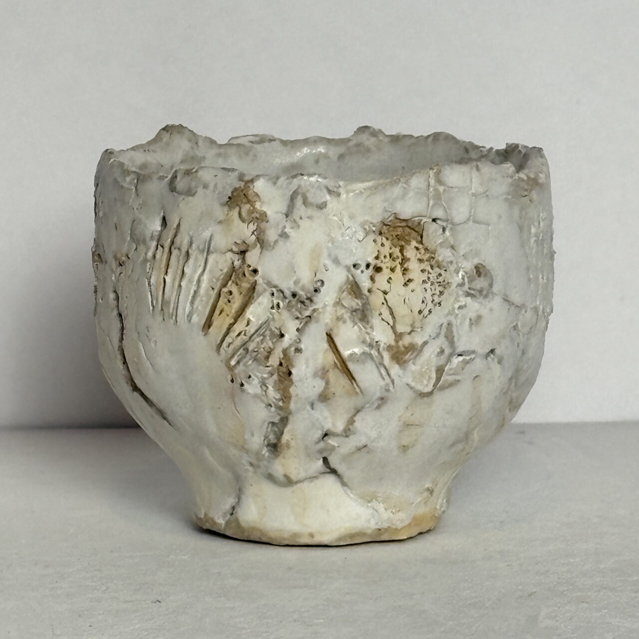 no. 90 Small ceramic vessel with white glaze, crackled surface, and carved textures with warm brown and gray accents.