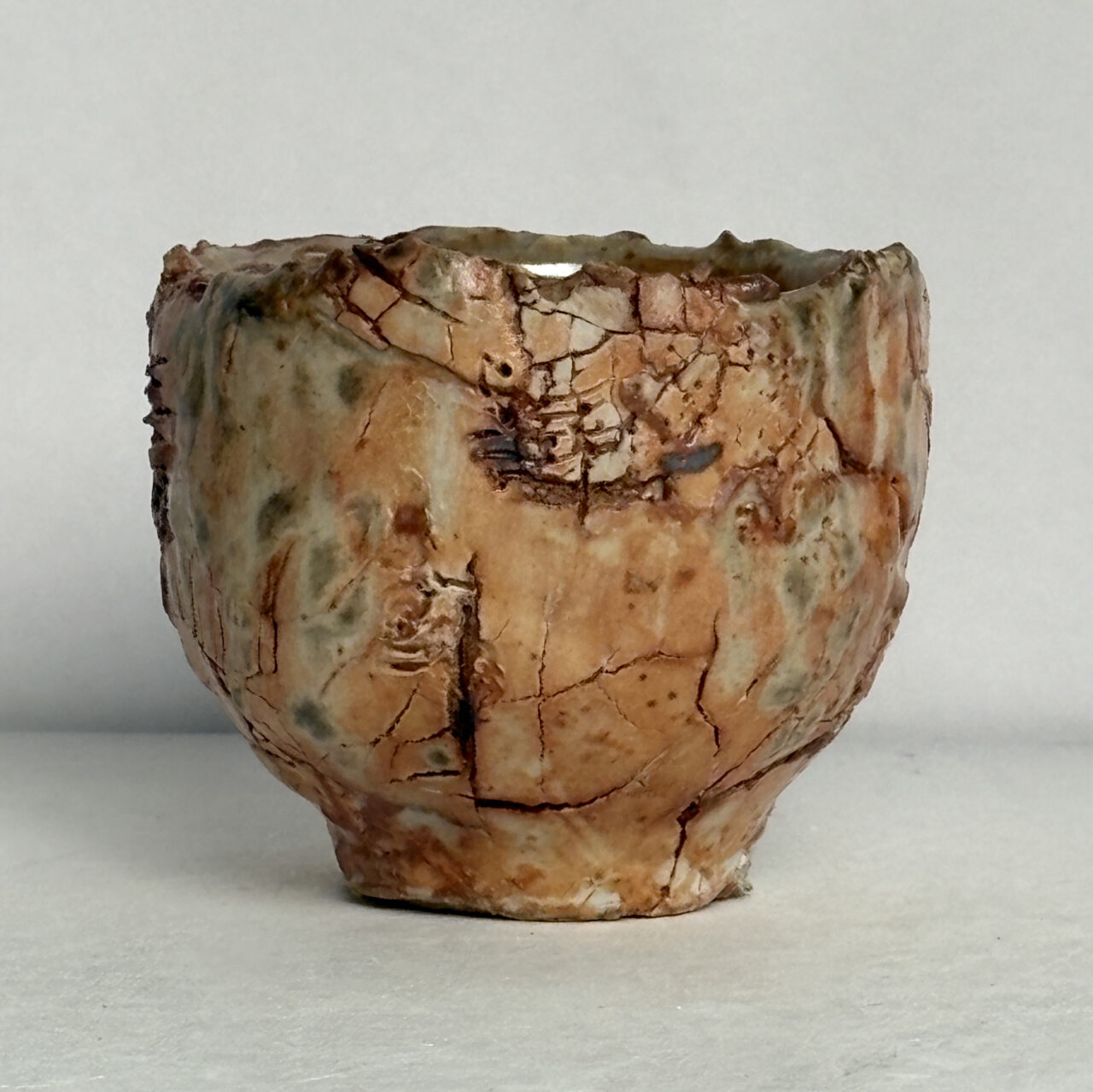 No. 95 Small ceramic vessel with warm peach and cream glazes, crackled surface texture, and soft gray-green markings with darker rust accents.
