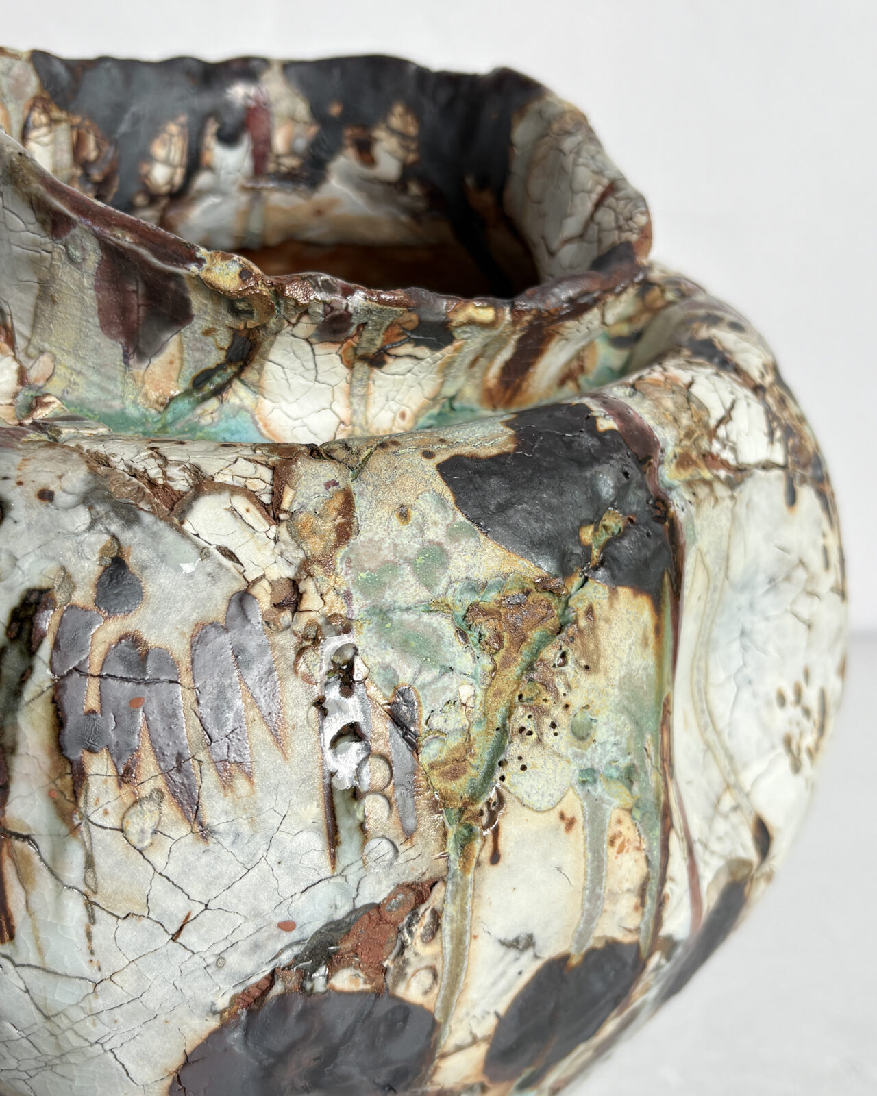 Detail view of Vessel No. 35 showing crackled white glaze, layered black and rust markings, and pale green glaze drips across the textured surface.