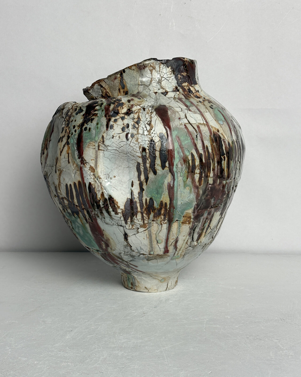 Side view of Vessel No. 35 with rounded form, vertical rust-colored drips, crackled white glaze, and dark layered surface markings.