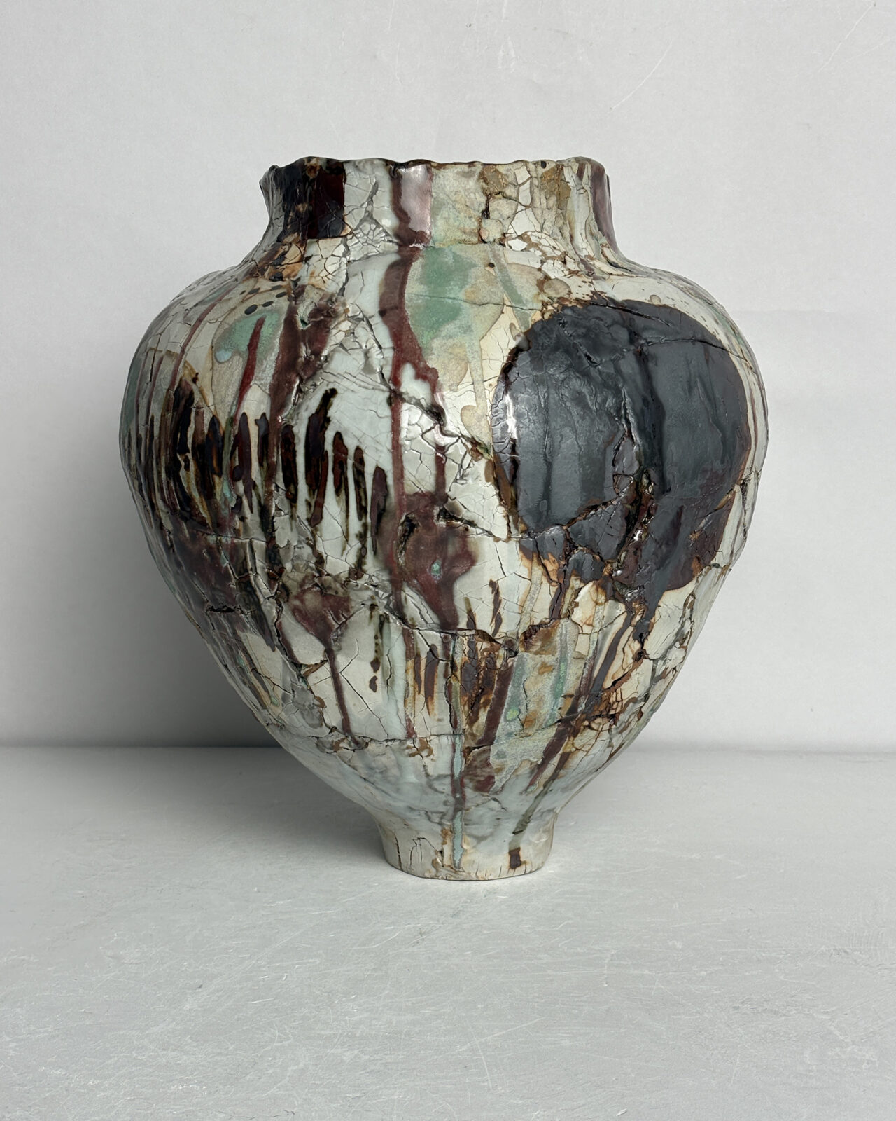 Alternate side view of Vessel No. 35 showing rounded silhouette, layered black and rust markings, pale green glaze washes, and crackled surface texture.