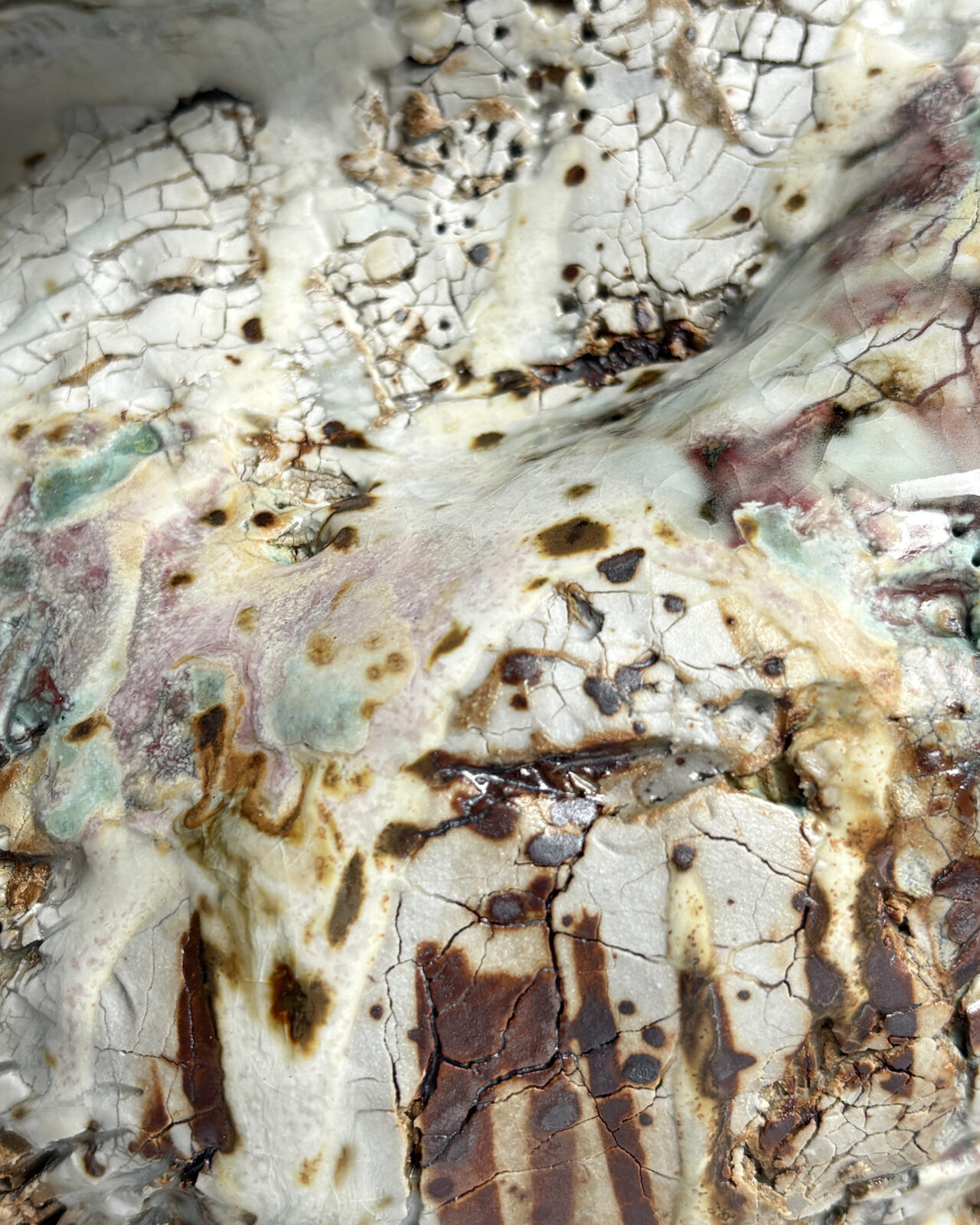 Texture detail of Vessel No. 43 showing crackled white glaze, layered rust and dark brown markings, and soft pale green and pink glaze variation across the sculpted surface.
