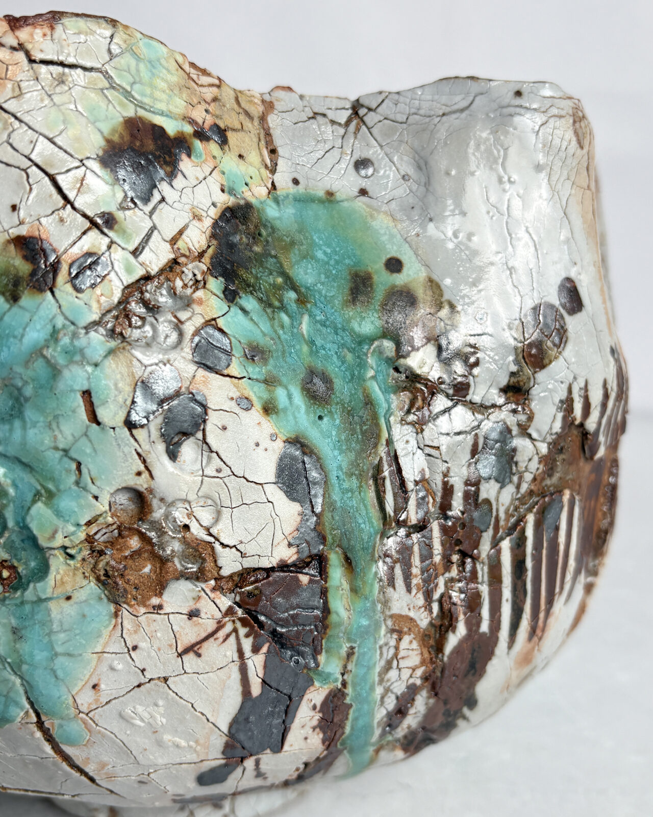 Detail view of Vessel No. 57 showing crackled white glaze, turquoise glaze drips, layered rust and dark brown markings, and textured surface variation.