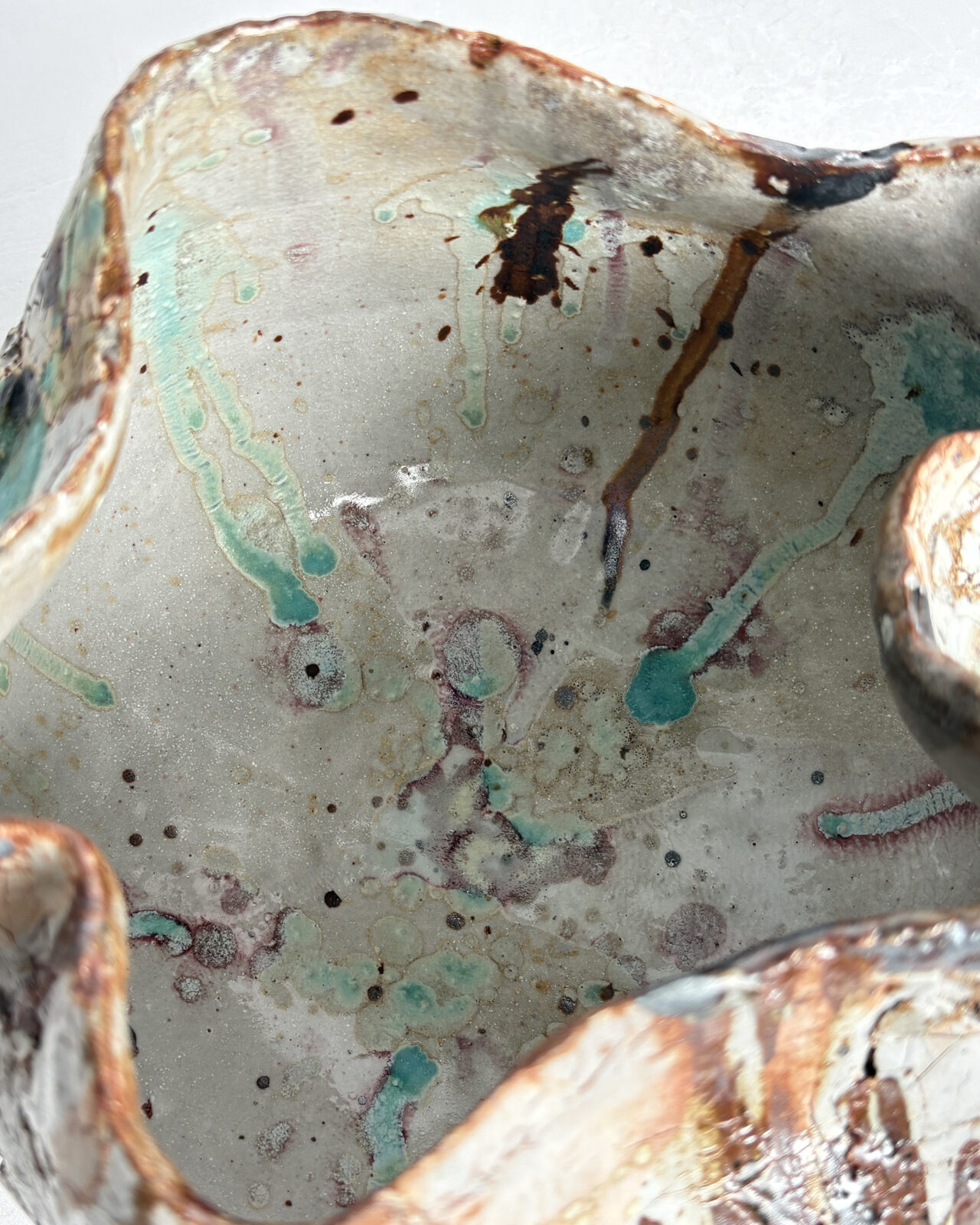 Interior rim detail of Vessel No. 57 showing sculpted opening, pale gray interior glaze, and turquoise and rust-toned glaze drips along the rim.