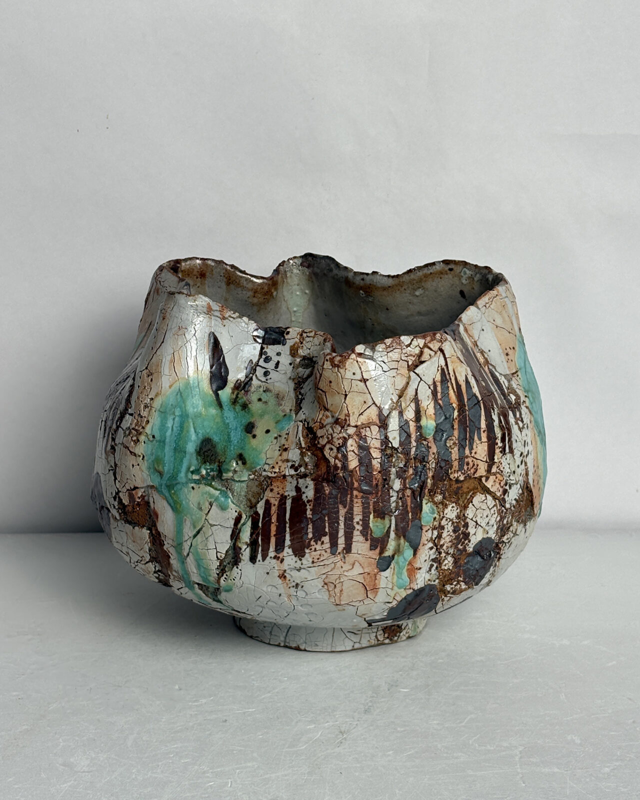 Alternate side view of Vessel No. 57 showing asymmetrical opening, turquoise glaze accents, crackled surface texture, and layered rust and dark brown markings.
