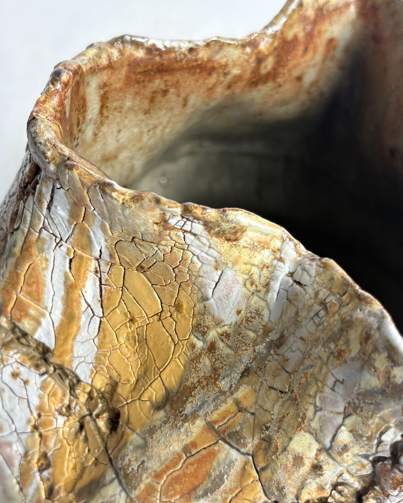 Vessel no. 58 Close-up of the irregular hand-formed rim with layered glaze, crackled surfaces, and warm atmospheric flashing from the soda firing process.