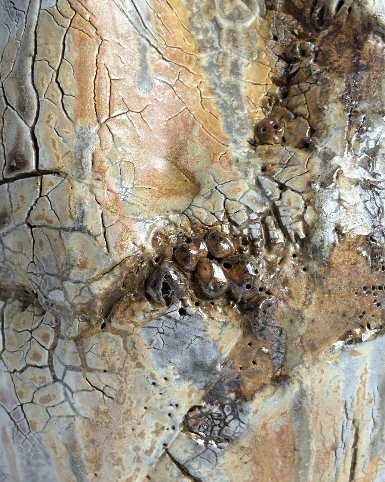 Macro detail of the vessel surface showing blistered glaze, crackle patterns, and layered atmospheric markings in ochre, cream, gray, and rust tones.