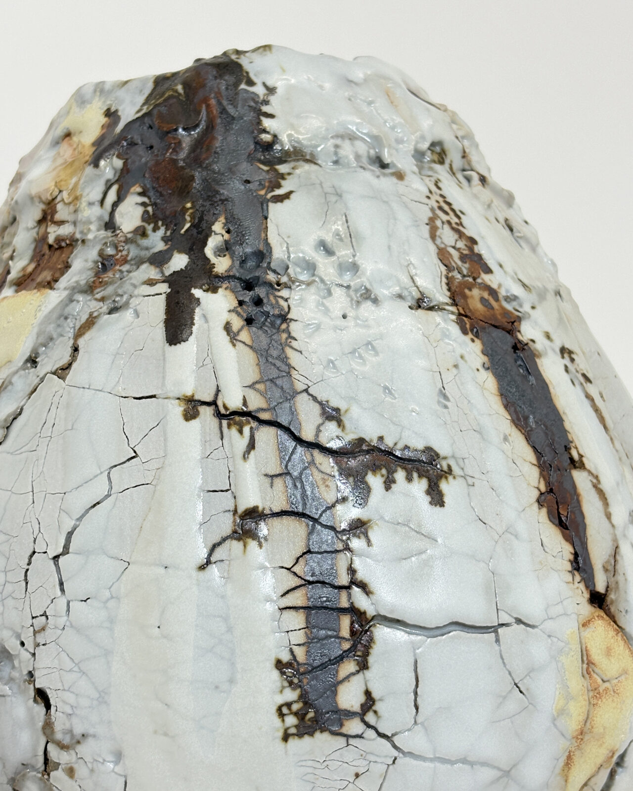 Vessel no. 68 - Close up detail of ceramic vessel with a cracked white surface and long drip of rust brown falling from rim down to belly