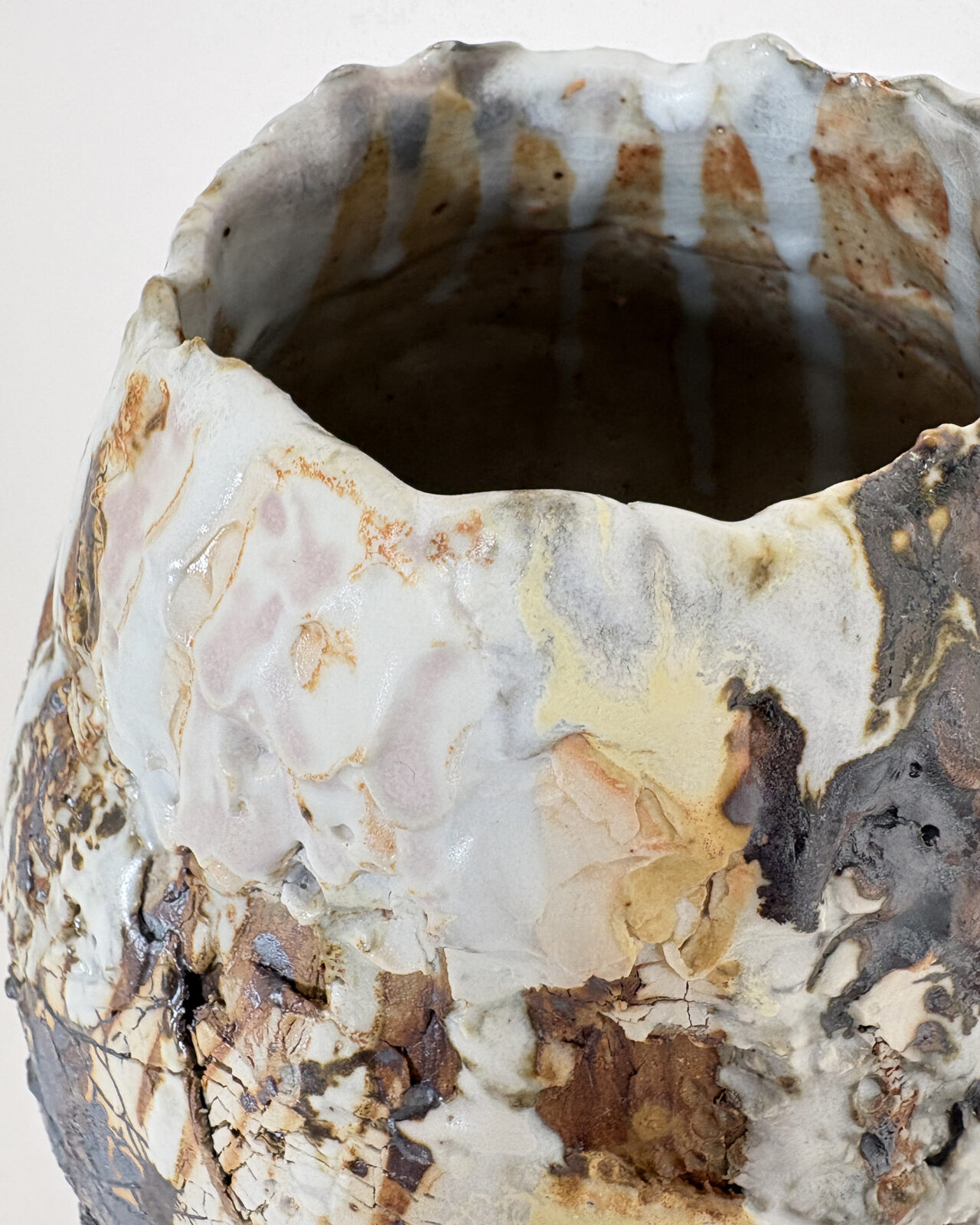 Vessel no. 68 - Close up detail of the rim of a ceramic vessel with a cracked white surface and long drip of rust brown falling from rim down to belly