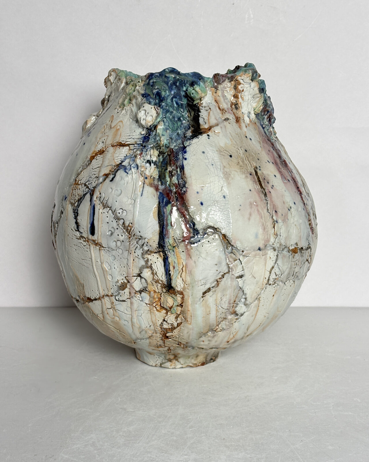 Vessel no. 66 - Side 1 - shows the vessel with glaze colors of off white, blue and turquoise with rust red areas in the cracked surface