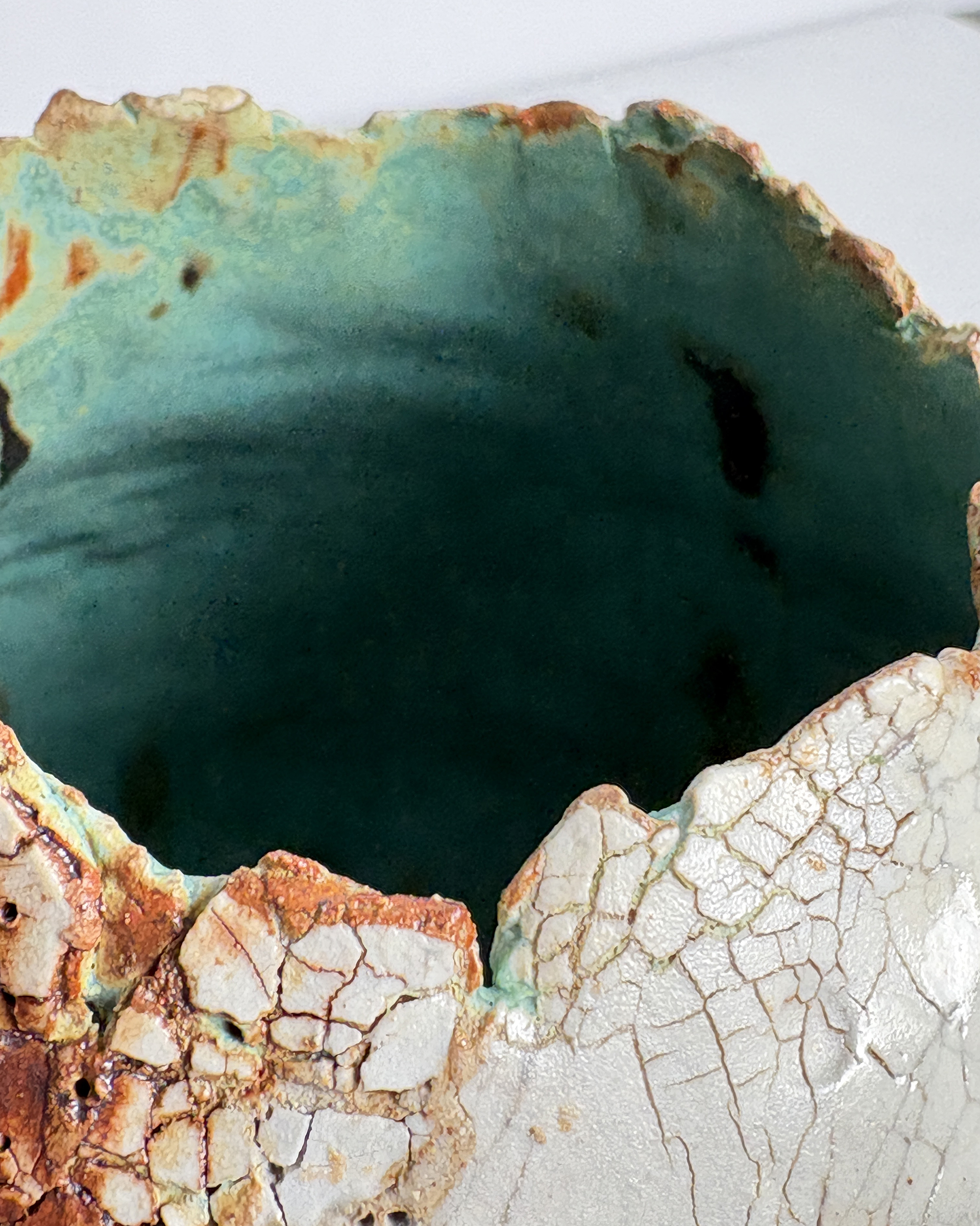 Vessel no. 69 - Detail image of rim of a ceramic vessel with deep turquoise blue interior and peachy rust oxide and white cracked surface texture.
