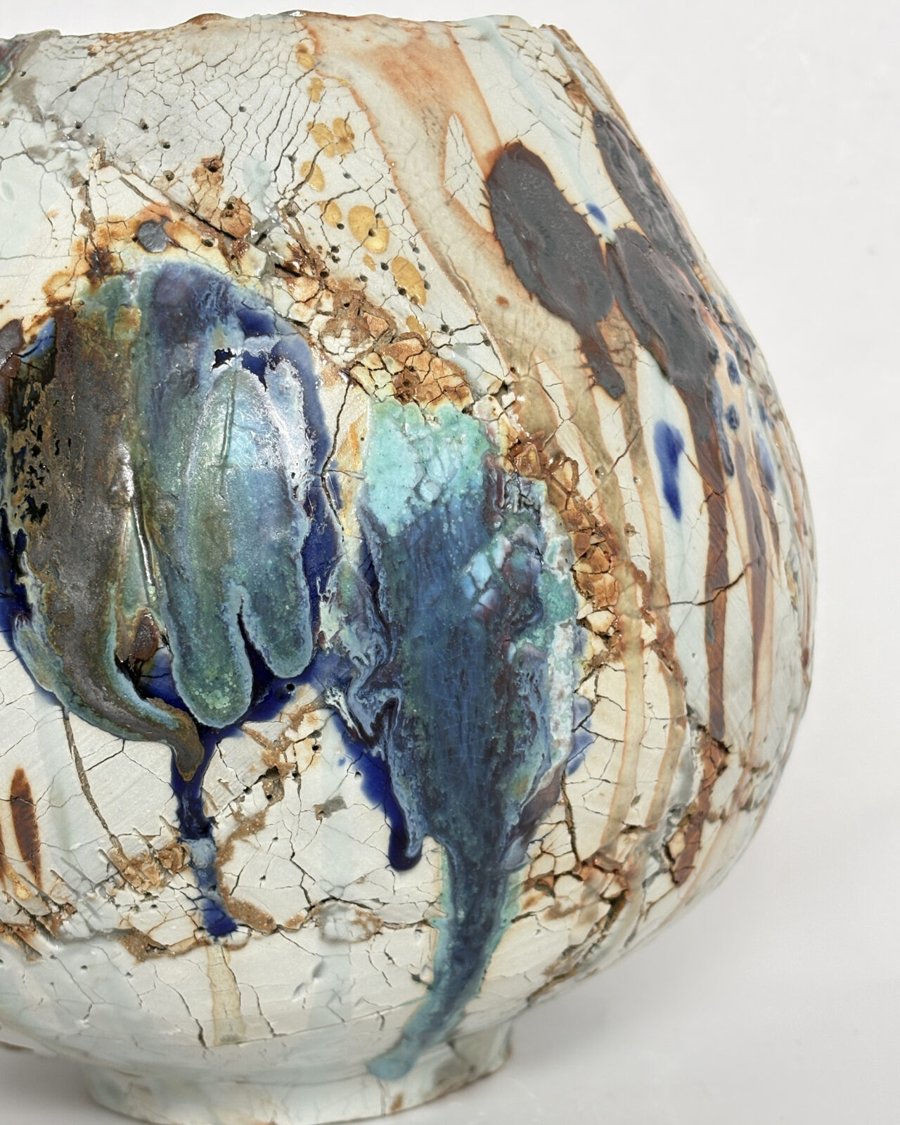 Vessel no. 70 - Detail of a ceramic vessel with 2 large china blue and turquoise dots bleeding over a warm white exterior