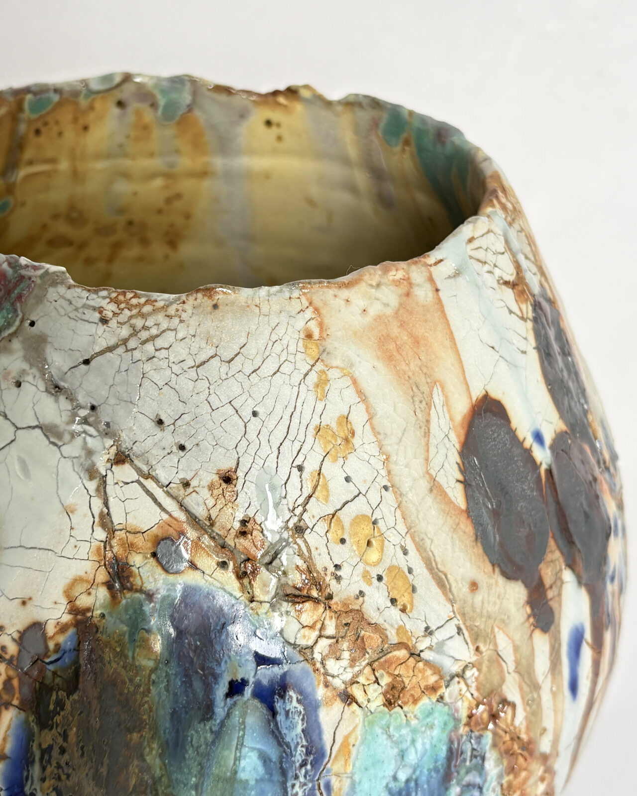 Vessel no. 70 - Rim detail of a ceramic vessel with 2 large china blue and turquoise dots and warm yellow interior