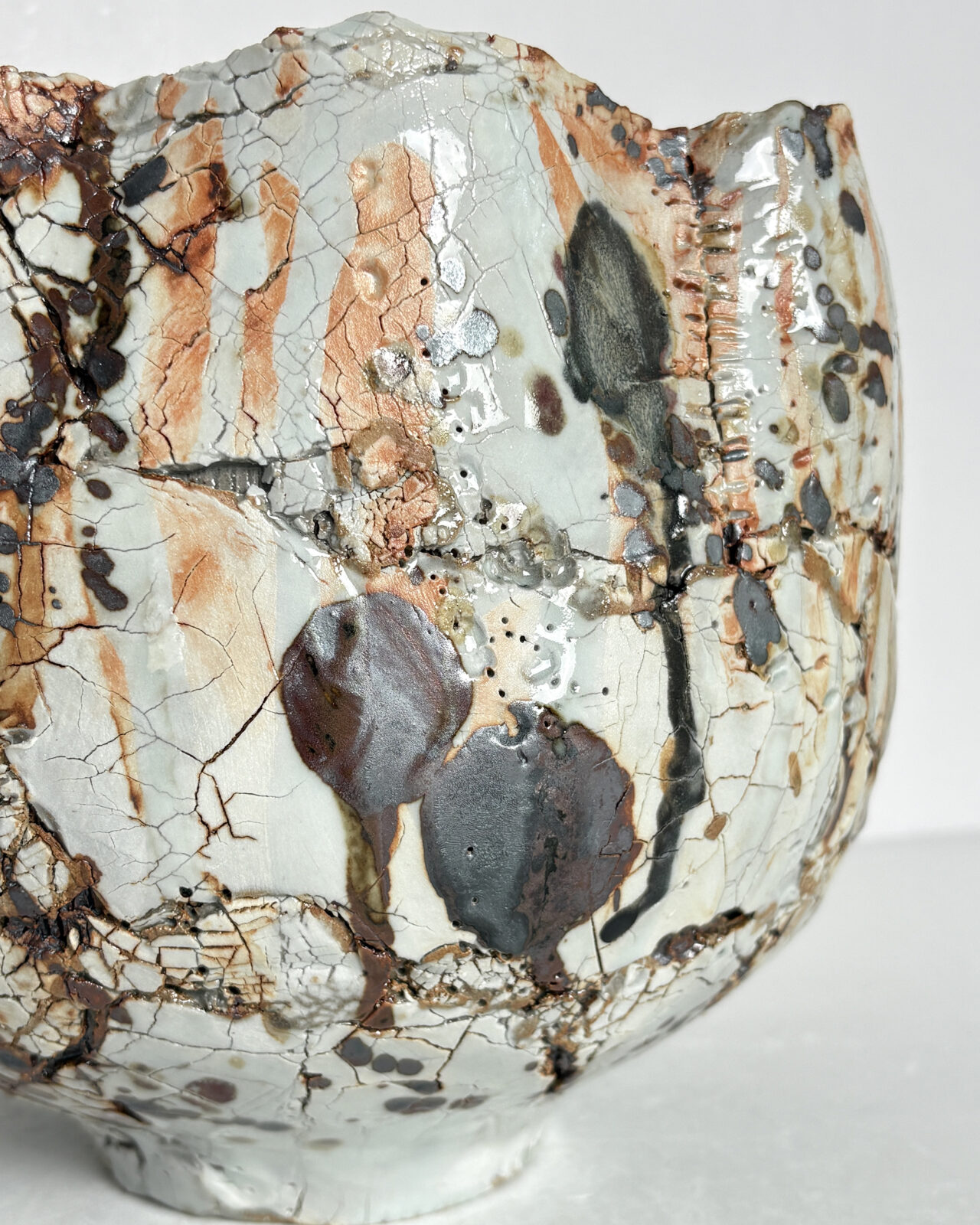 Vessel no. 72 - Detail of a ceramic bowl shaped vessel with a fluted edge and rust brown marking on a creamy white textured surface