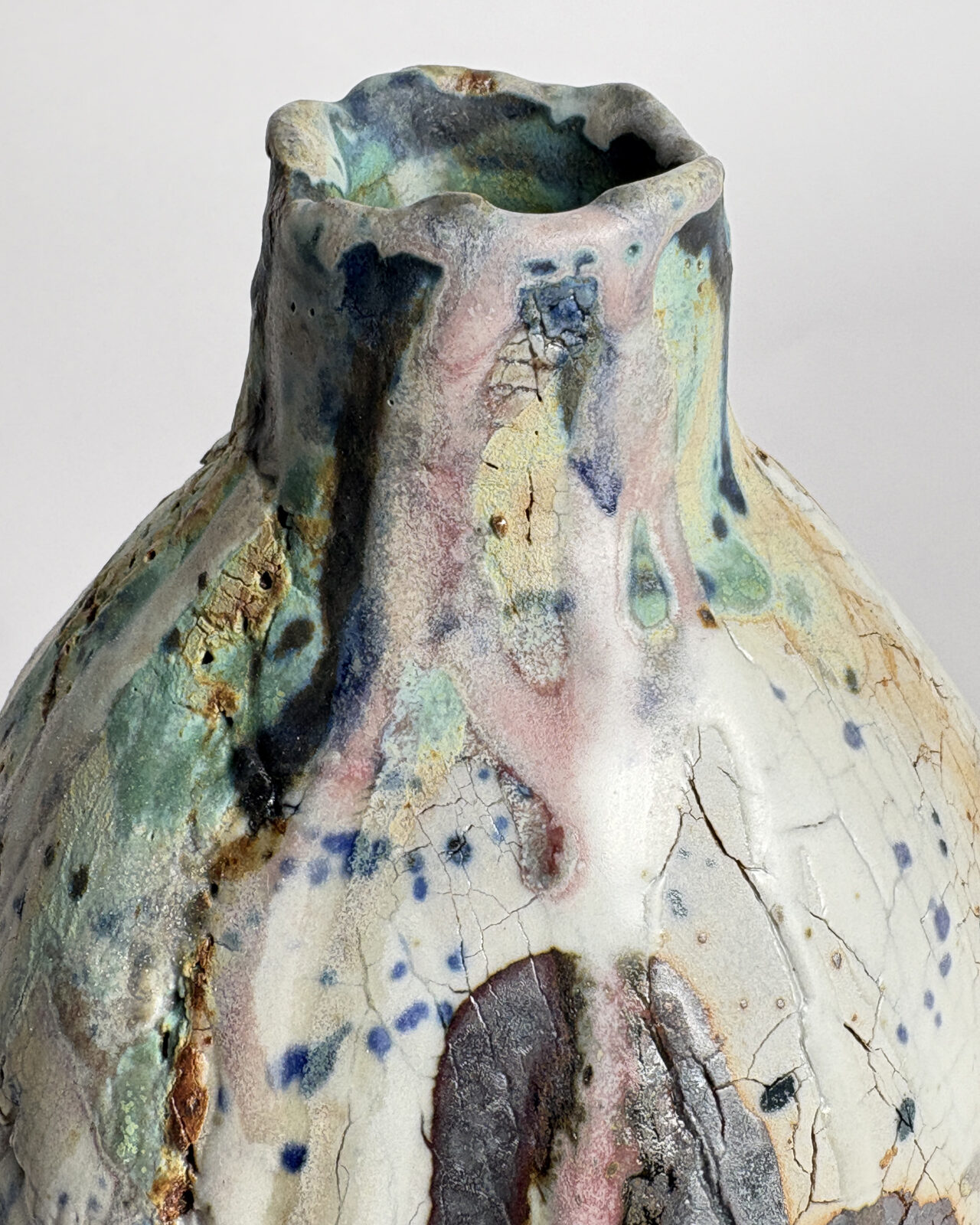 Detail of Vessel No. 61 showing layered ceramic glazes in turquoise, blue, pink, and cream over a cracked, weathered surface.