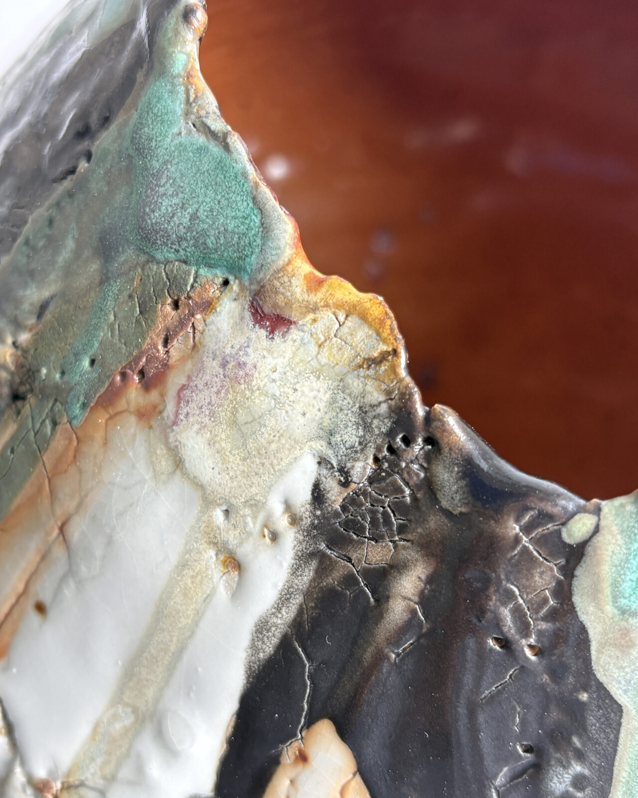 Close-up of the irregular rim of Vessel No. 73 with turquoise, charcoal, cream, and metallic glazes surrounding a warm rust-colored interior.