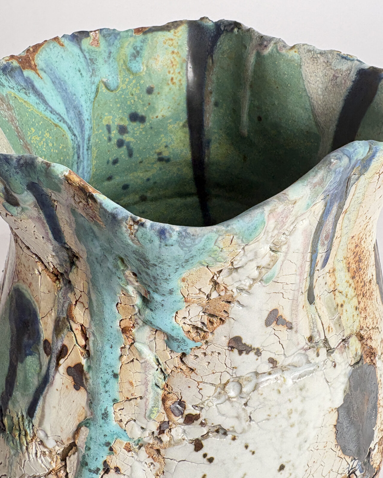 Detail of the rim of Vessel No. 73 showing fine crackling, layered turquoise and blue oxide glazes, dark linear rust-colored marks on the ceramic surfaces.